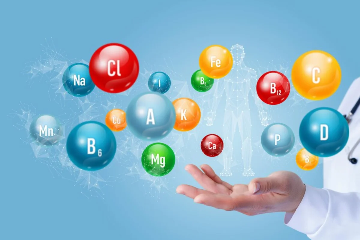 A digital image depicting a healthcare professional’s hand interacting with floating, colourful spheres labelled with various vitamins and minerals