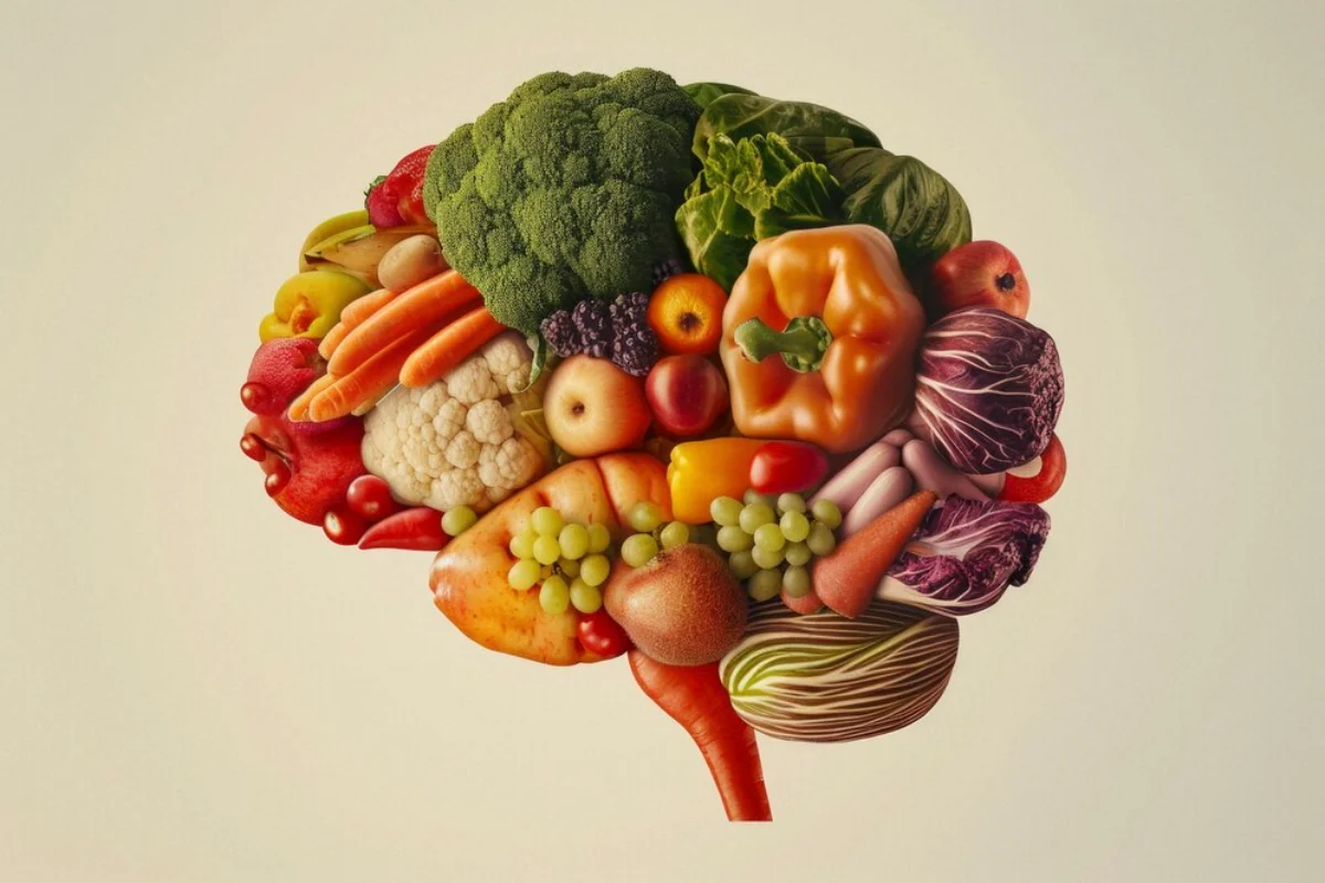 An artistic representation of a human brain composed of various fruits and vegetables such as broccoli, carrots, and grapes