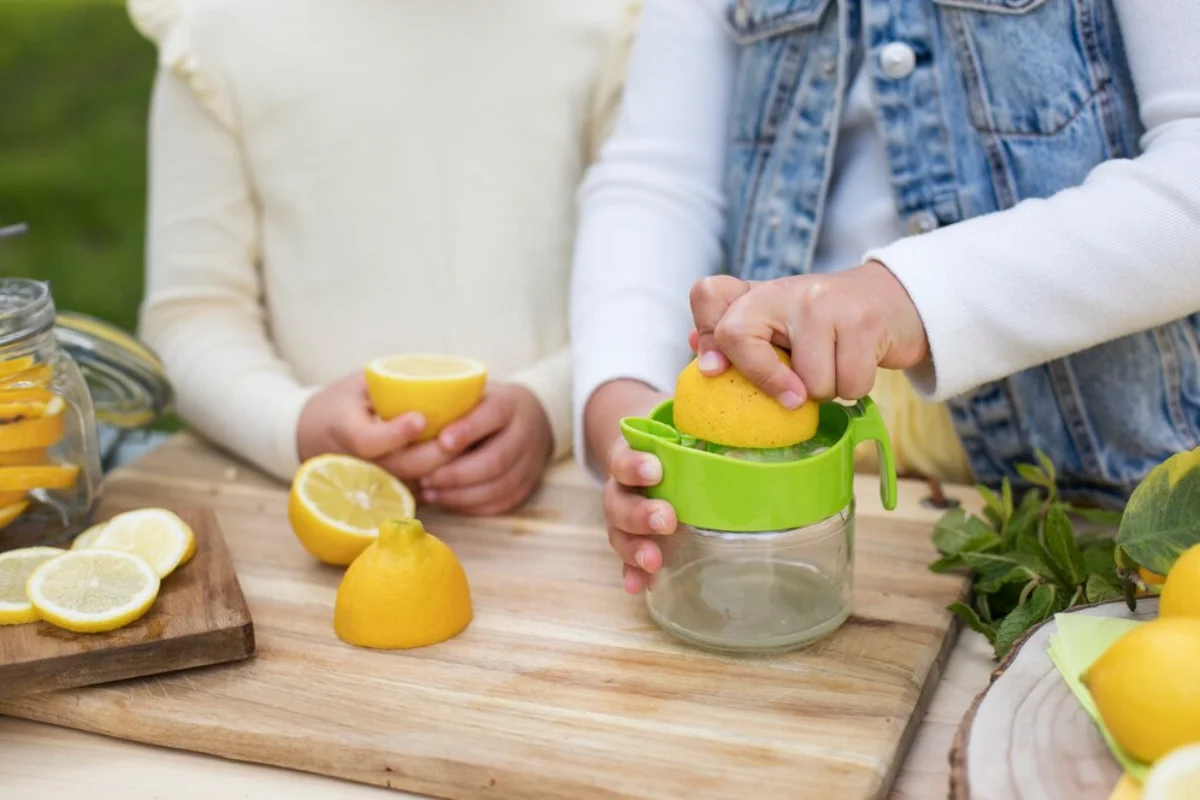 Child using a lemon squeezer to make lemonade with fresh lemons