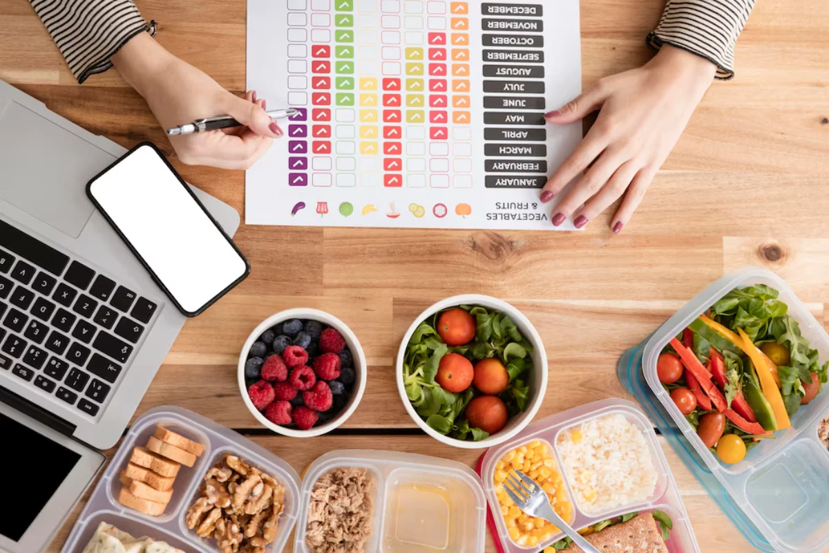 A person planning a meal with a detailed nutrition chart, surrounded by a variety of healthy foods