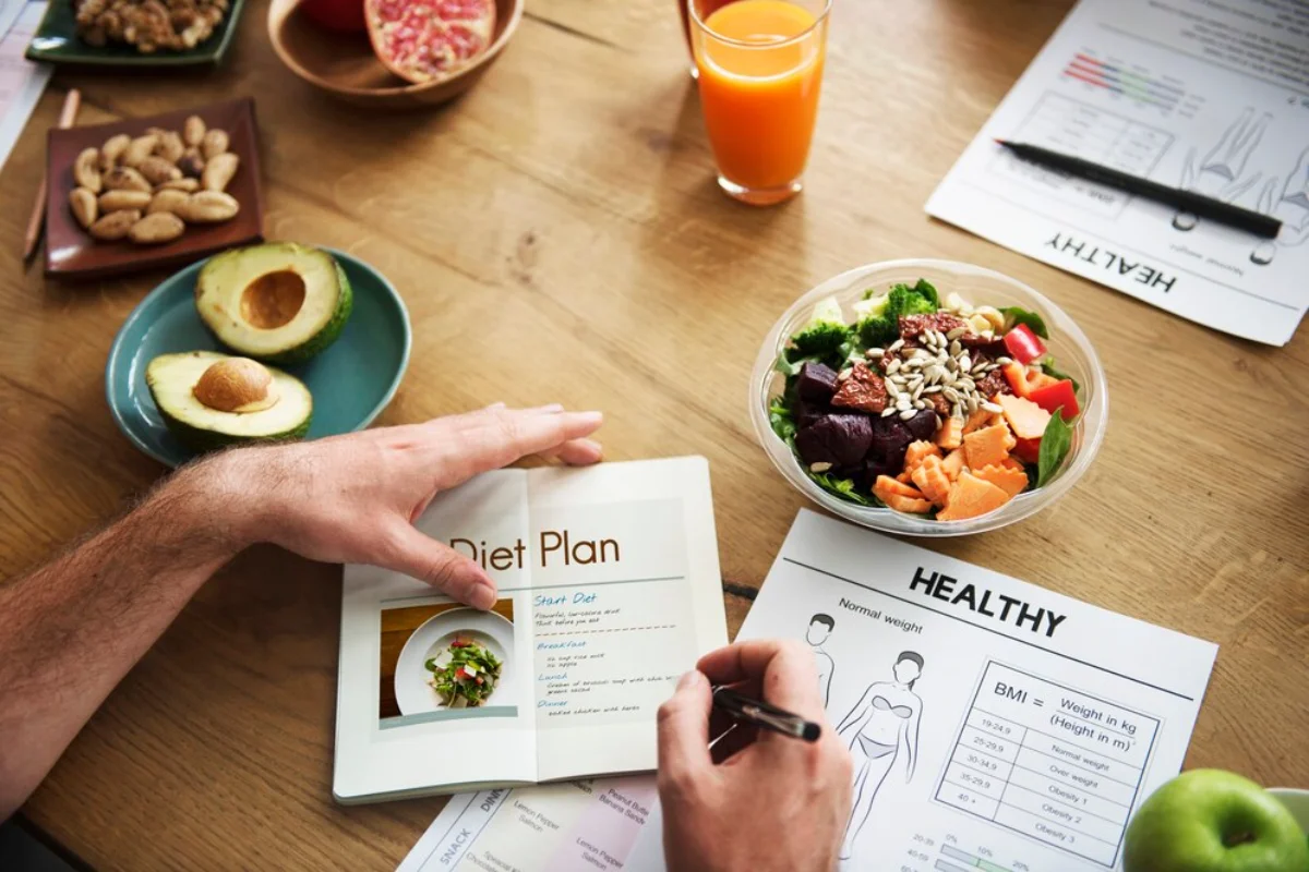 A person plans a healthy diet, with open books showing diet plans and healthy eating charts