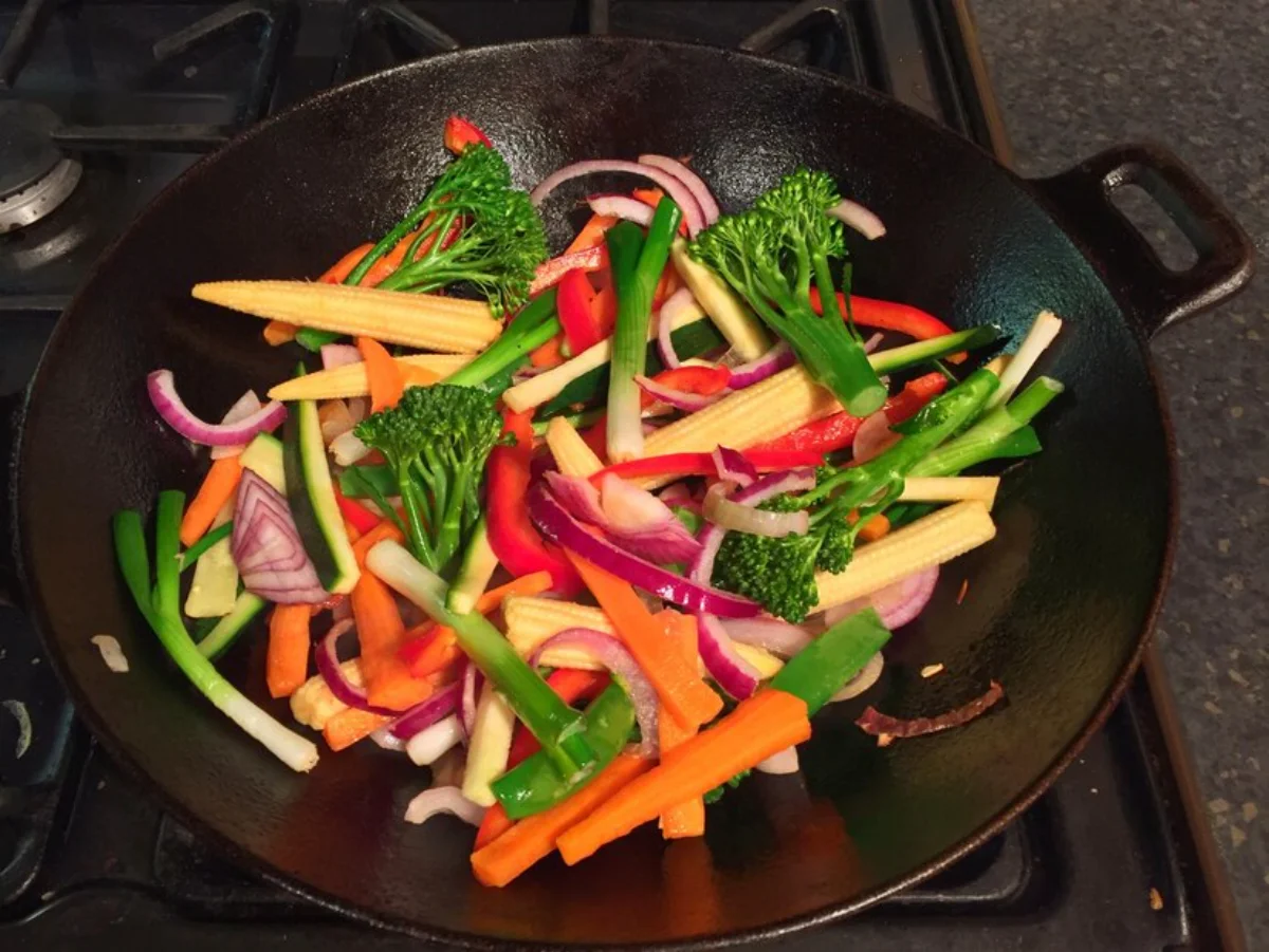 A variety of colourful stir-fried vegetables including broccoli, carrots, red and green bell peppers, and red onions