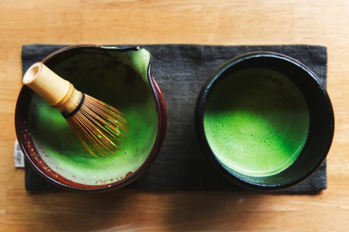 Top view of two ceramic bowls on a slate board with freshly whisked matcha green tea