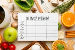 An overhead shot of a weekly meal plan notepad surrounded by various healthy foods including fruits, vegetables, nuts, and eggs