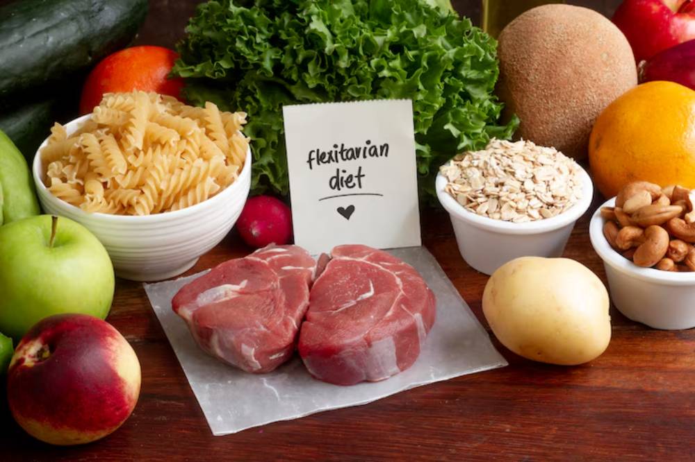 Assorted fresh foods for a flexitarian diet, including vegetables, fruits, pasta, meat, oats, nuts, and a handwritten note.